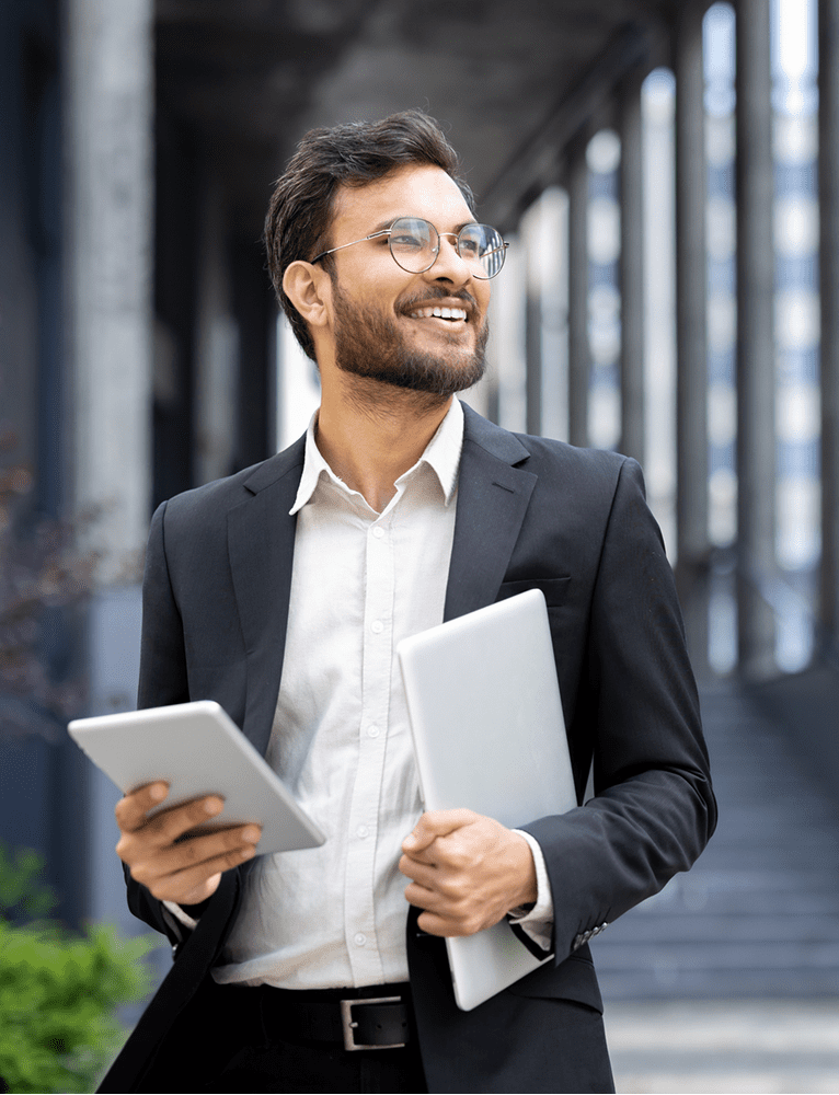 Man in suit holding tablet and laptop.
